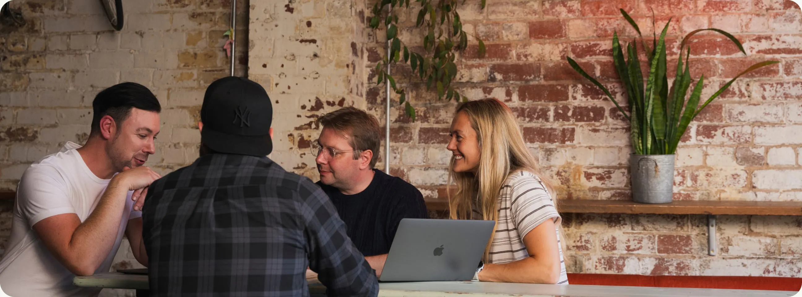 Four of the team working together around a laptop in the studio