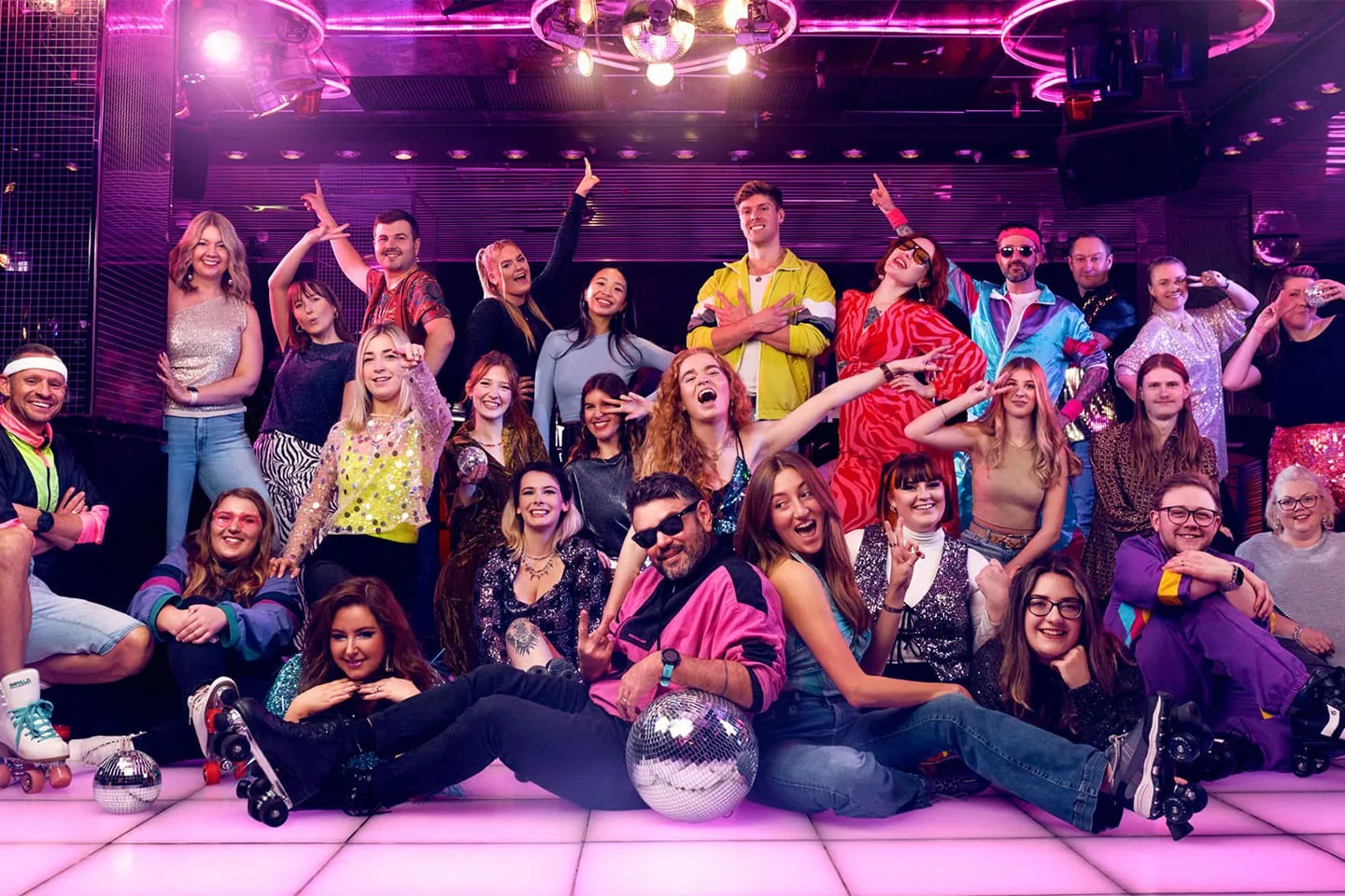 A crowd celebrating under pink and blue lights at a Boutique event