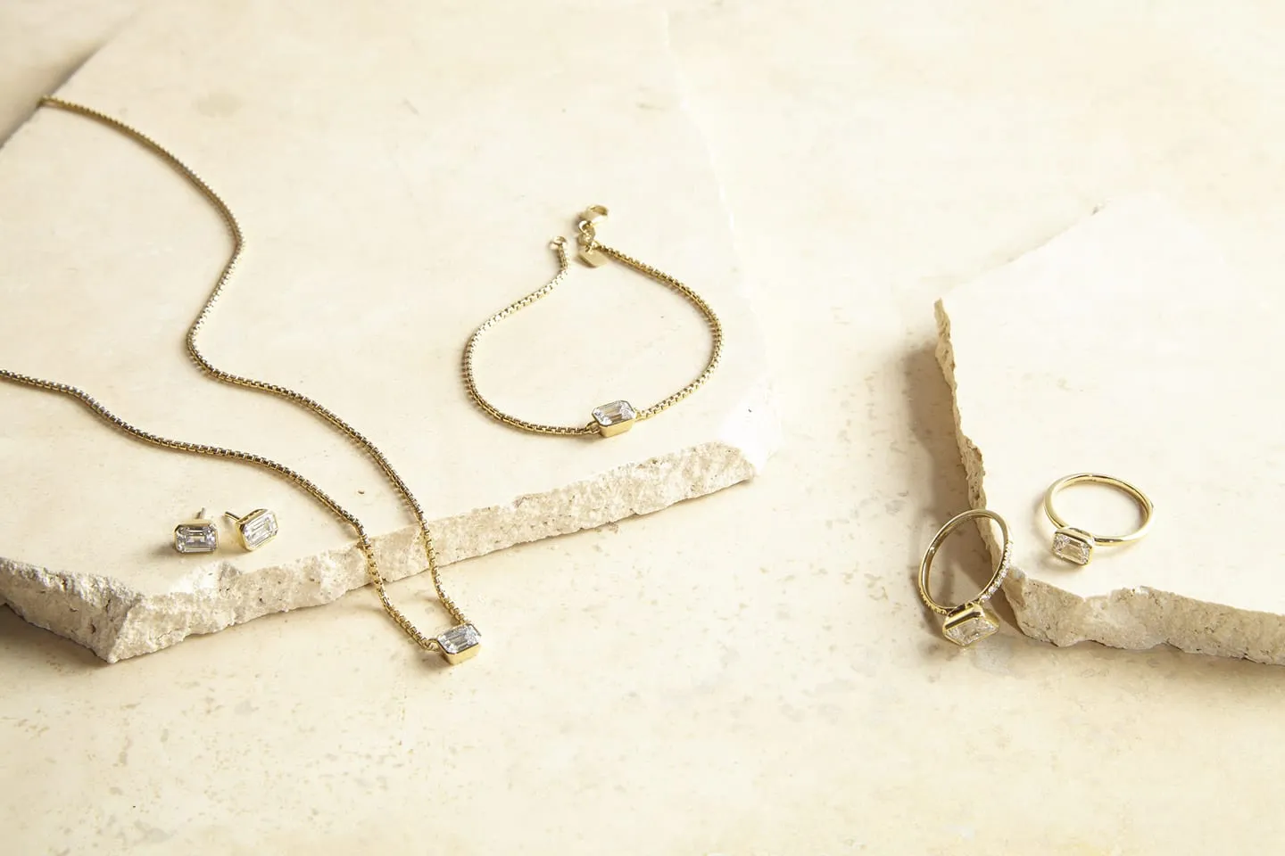 Fine gold jewellery laid out on a pale stone surface