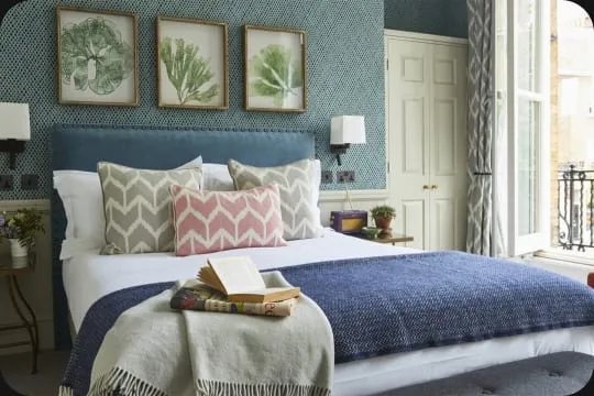 A bedroom at the Lime Tree Hotel with a blue headboard and patterned cushions