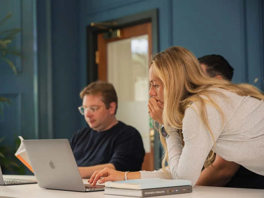 Two of the team leaning over a laptop together in the studio
