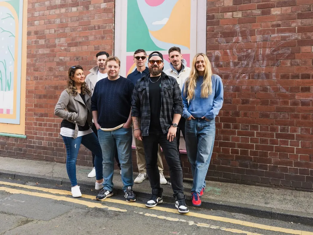 The Adigi team standing together on a street beside a mural