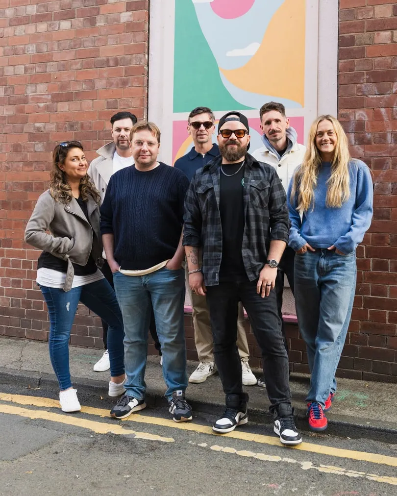 The Adigi team standing together on a street beside a mural