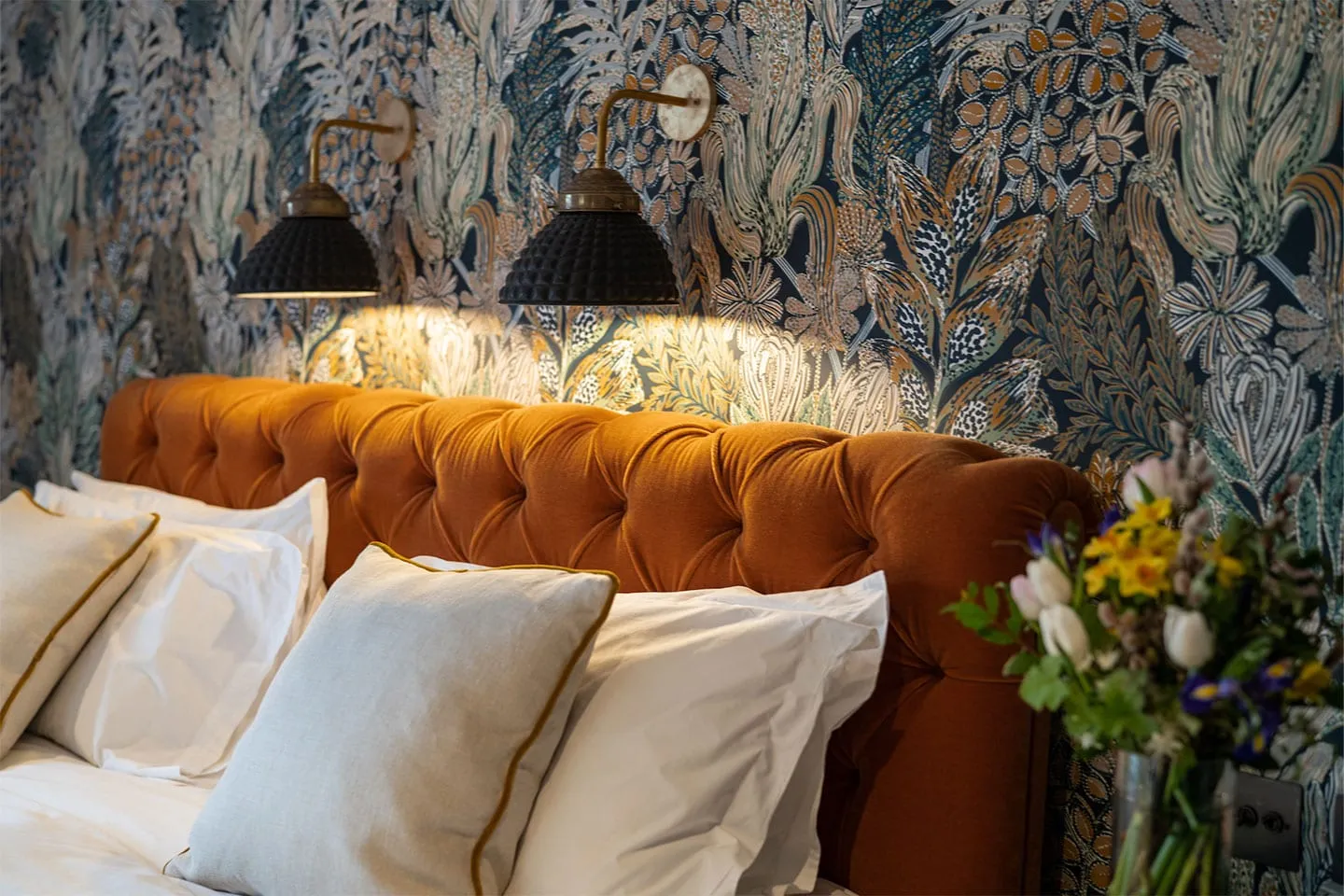 A bed with a velvet headboard and cushions in a Country Creatures room