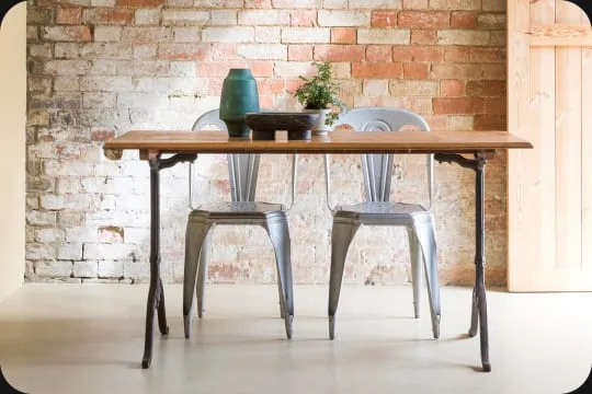 A Merchant & Found dining table and metal chairs against a brick wall
