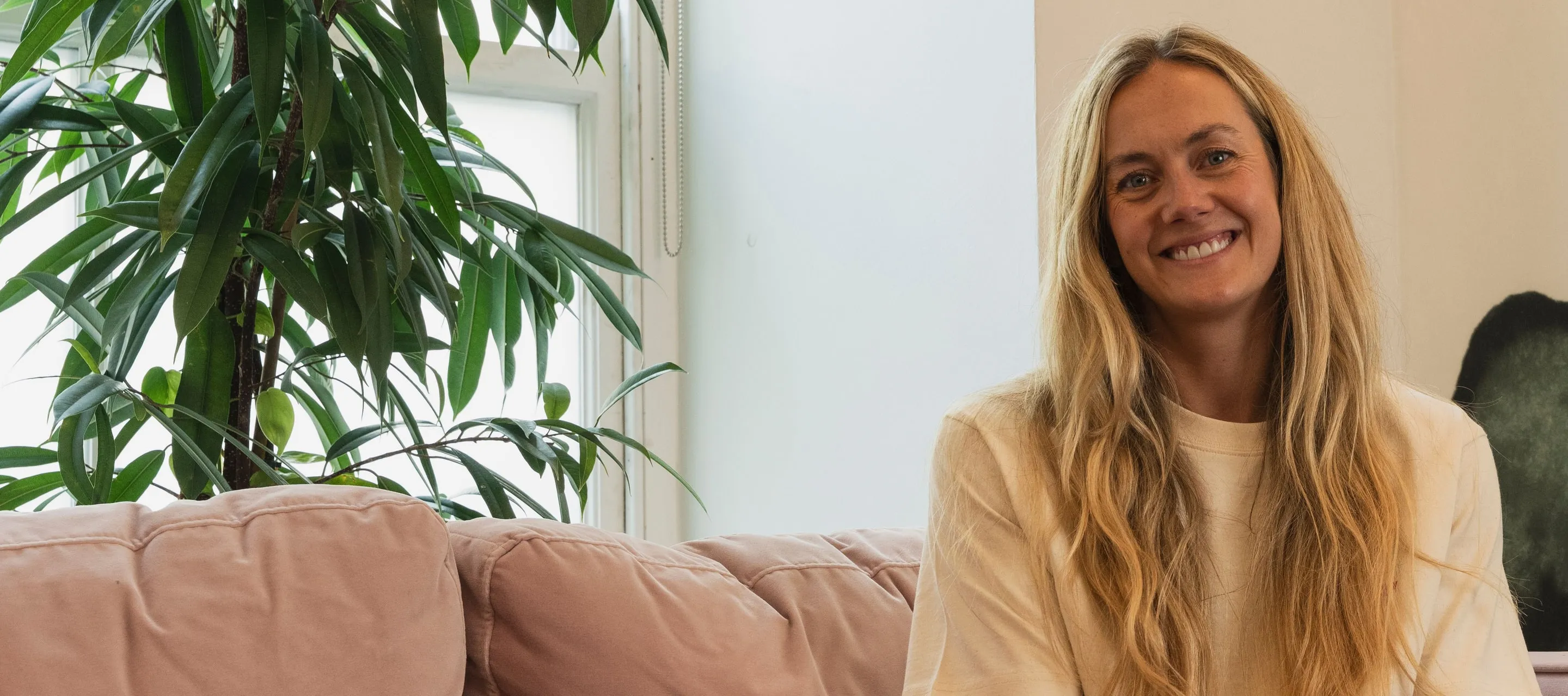 Em Thornton smiling, sitting on a sofa in the studio
