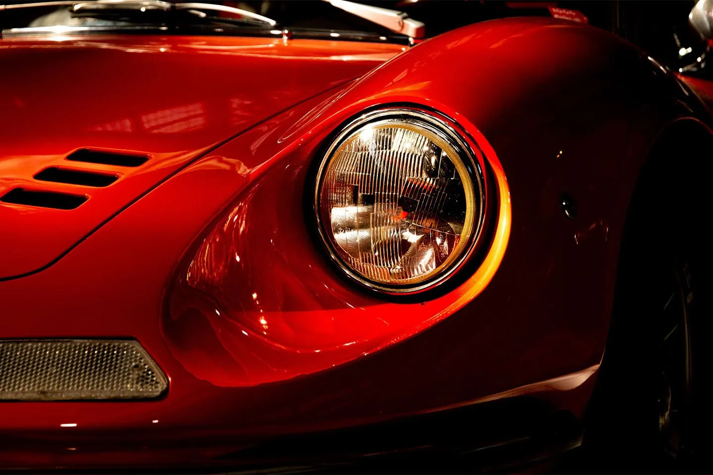 The headlamp and red bodywork of a classic car, close up