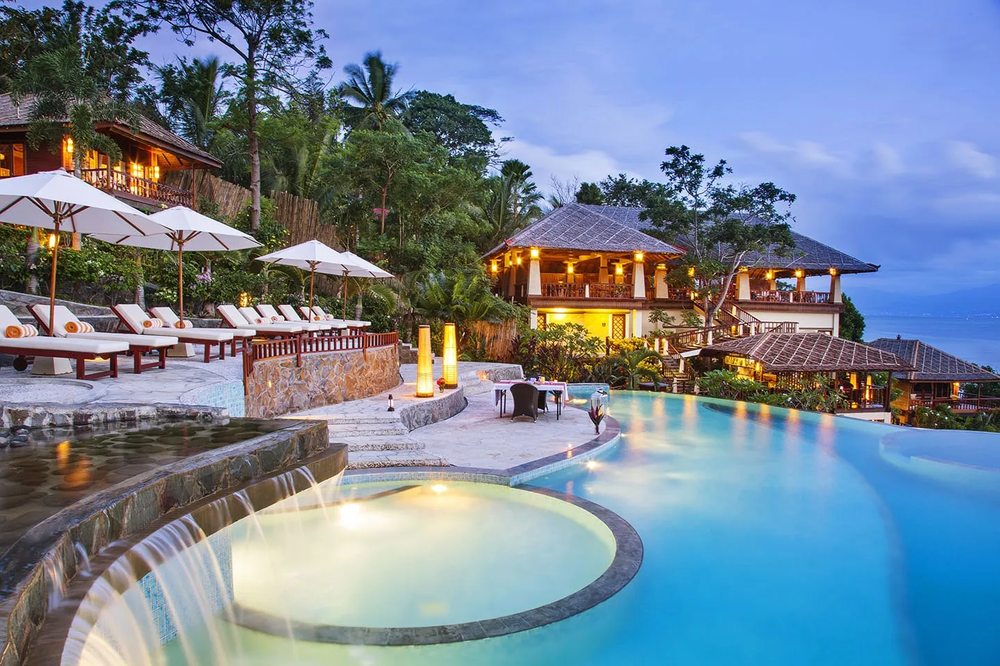 The pool and bar at Bunaken Oasis at dusk, among the palms