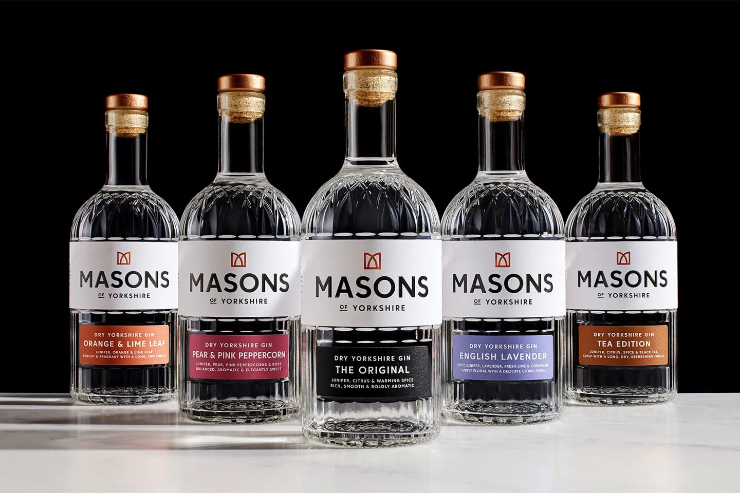 A row of Masons of Yorkshire gin bottles on a dark background