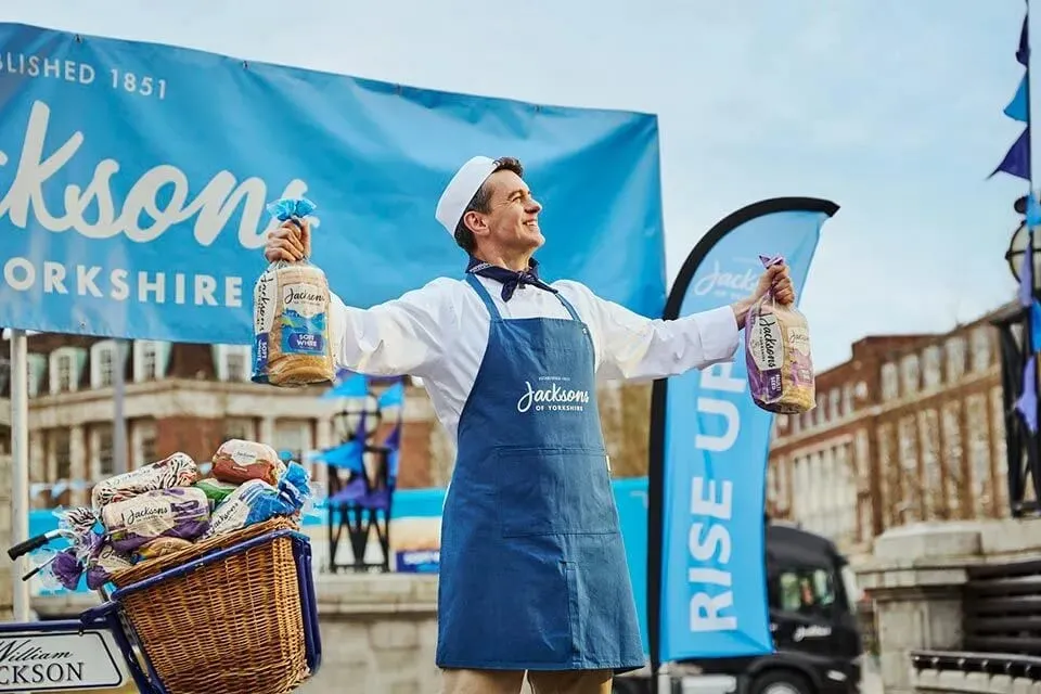 A Jacksons of Yorkshire baker handing out bread at an outdoor event
