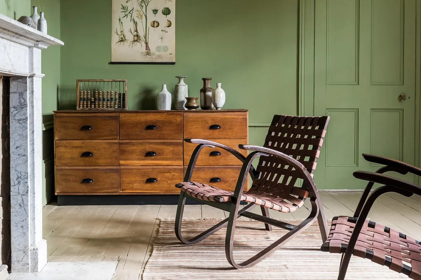 A room with a wooden sideboard and a rocking chair, furnished by Merchant & Found