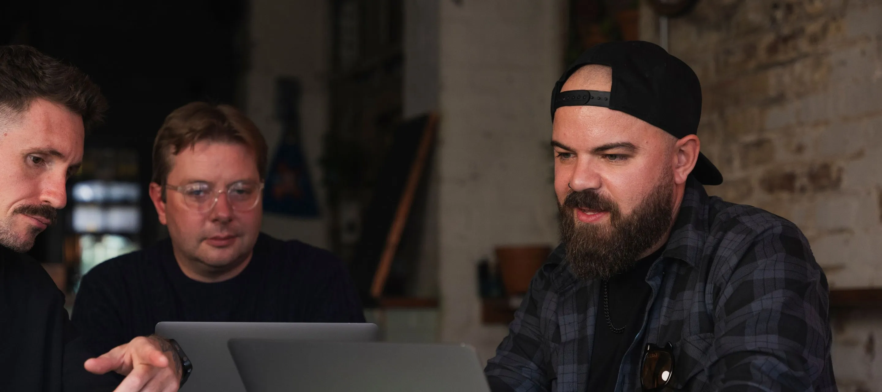 Ollie Lewis working at a laptop with Sam and Kev