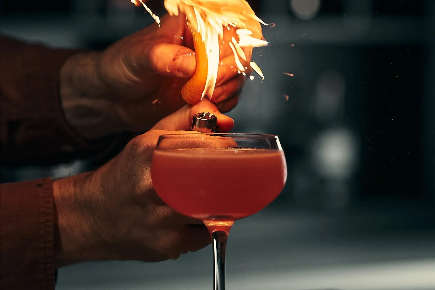 A cocktail being garnished with a flame