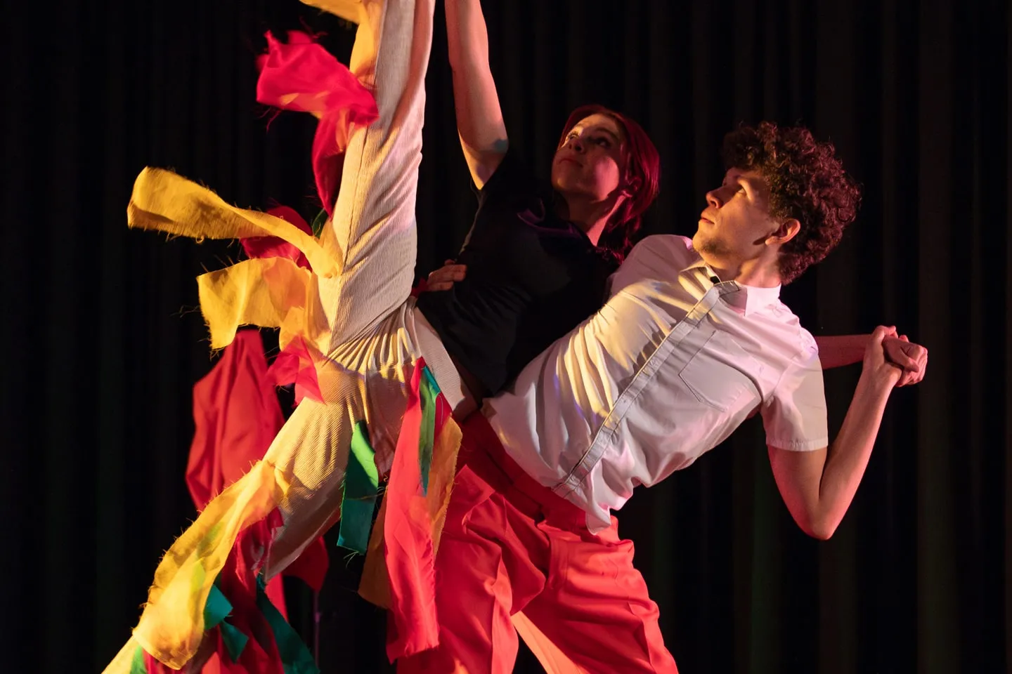 RJC Dance performers in red and yellow mid-leap