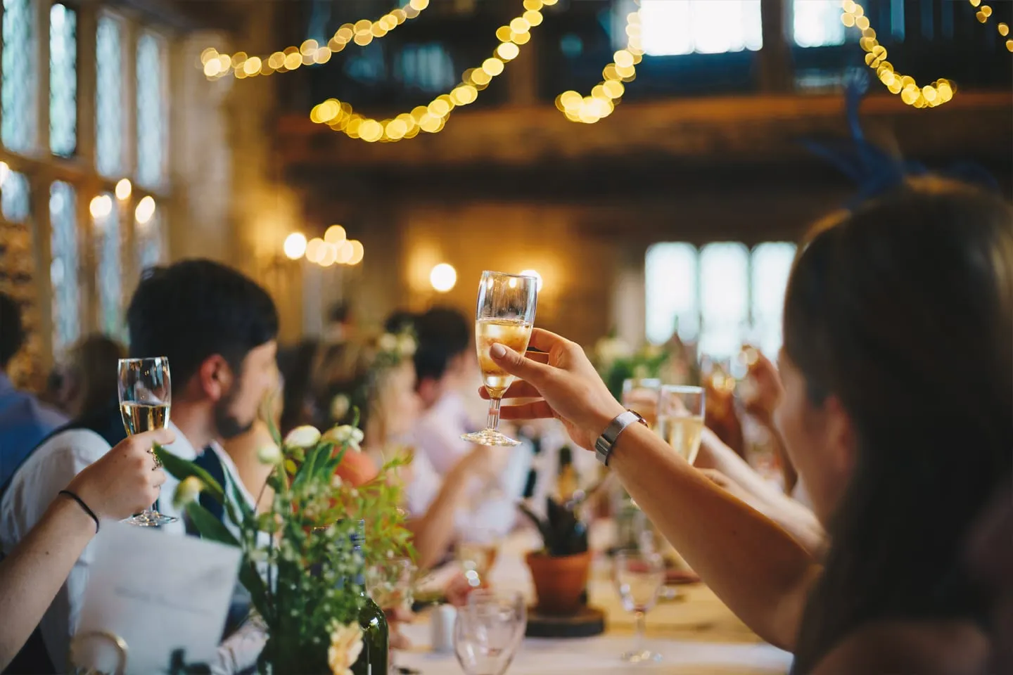 Guests raising glasses at a candlelit dinner at Sandburn Hall