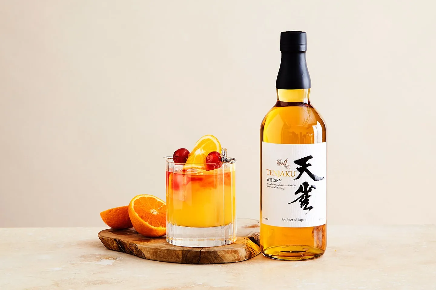 A bottle of Tenjaku whisky beside an orange cocktail