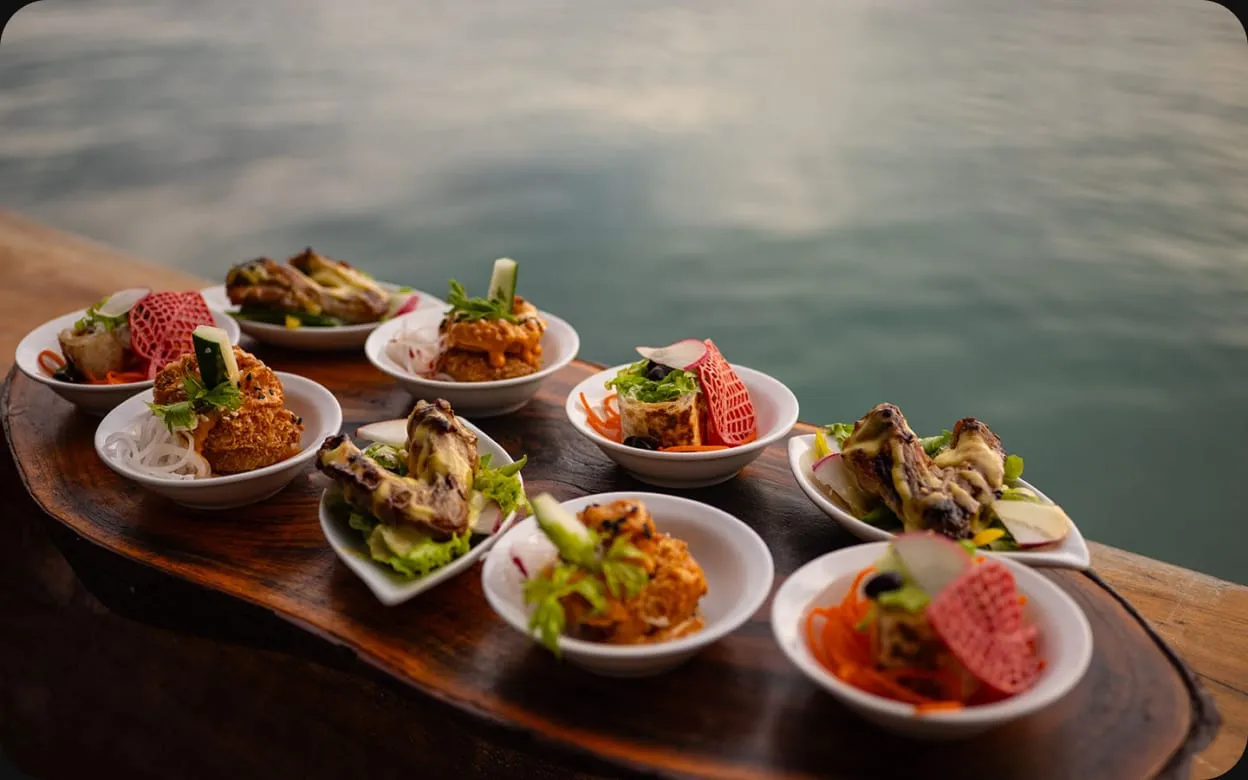 Small plates of food served on a wooden board by the sea