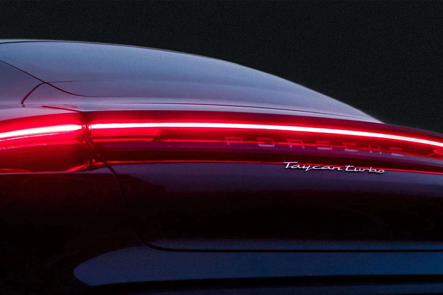 The rear lights of a red Porsche Taycan at night