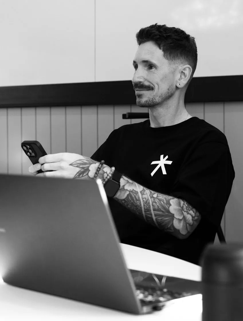 One of the team smiling at his laptop, in black and white