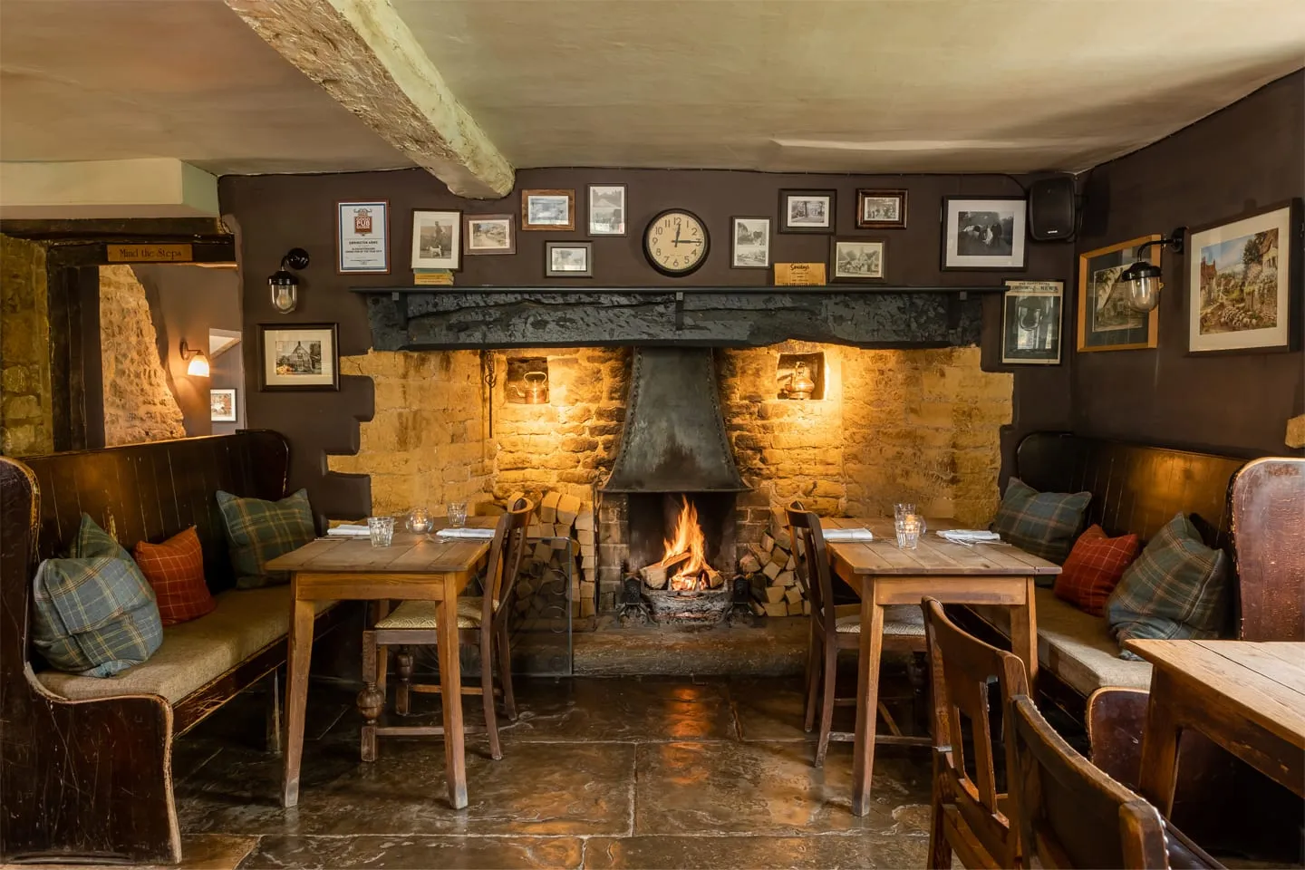 A cosy pub interior with a fire and wooden tables